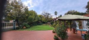 a patio with an umbrella and a yard with a fence at Bloemhoek Guest House in Centurion