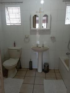 a white bathroom with a sink and a toilet at Bloemhoek Guest House in Centurion