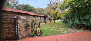 a brick house with a brick fence and a yard at Bloemhoek Guest House in Centurion
