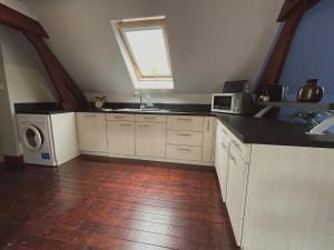 a kitchen with white cabinets and a sink and a window at Jolie chambre sous les toits in Dreux