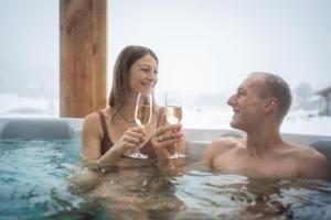 a man and woman drinking champagne in a bathtub at Chalet Auszeit im Schönseer Land in Schönsee