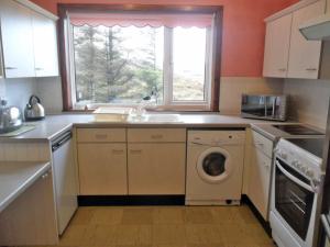a kitchen with a washing machine and a window at Ken Maree in South Erradale