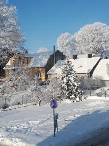 a snow covered street with a house and a sign at Cozy city centre apartment in Telšiai