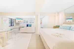 a white bedroom with a large bed and a couch at Sandcastle Beach House in The Valley +55 photos