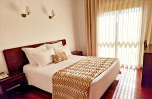a bedroom with a large bed with a large window at Hotel Vale Do Côa in Vila Nova de Foz Coa