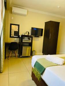 a bedroom with a bed and a desk and a tv at Bayside Hotel 97 Russell Street in Durban