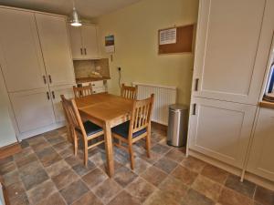 a kitchen with a wooden table and chairs at Cosy Cottage in Warkworth