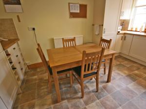 a kitchen with a wooden table and chairs at Cosy Cottage in Warkworth