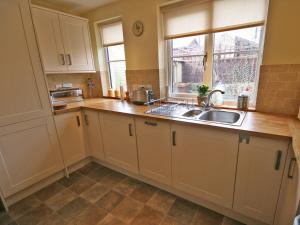 a kitchen with white cabinets and a sink at Cosy Cottage in Warkworth