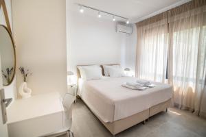 a white bedroom with a bed and a window at Maison Poème Luxury Apartments in Aiándion