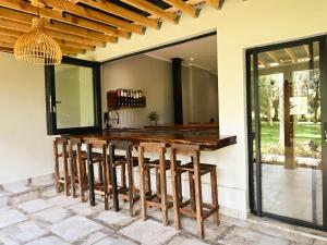 an outdoor kitchen with a wooden bar with stools at The Roaming Goat Guesthouse in Toekoms