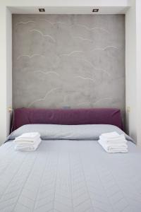 a white bed with two towels on top of it at Art-inn in San Vendemiano