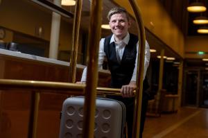 a man in a vest and tie holding a suitcase at Dombås Hotel in Dombås +10 photos