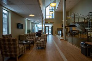 a lobby with chairs and tables and a staircase at Dombås Hotel in Dombås