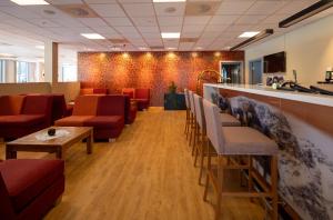 a waiting room with red chairs and a bar at Dombås Hotel in Dombås