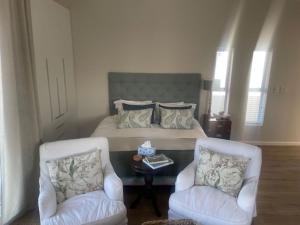 a bedroom with a bed with two chairs and a table at Blissful Barons View in Plettenberg Bay