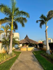 a walkway with palm trees and a thatch hut at Casa completa en Acapulco in Acapulco