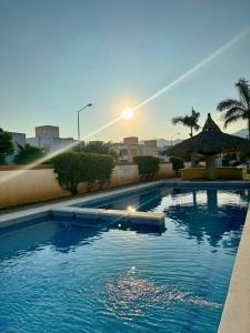 a swimming pool with the sun setting in the background at Casa completa en Acapulco in Acapulco