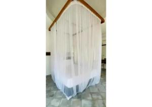 a bed with white curtains hanging from a wall at Mango Villa Mtwapa in Mtwapa +38 photos