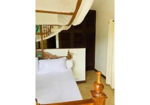 a bedroom with a bed with white sheets and a window at Mango Villa Mtwapa in Mtwapa