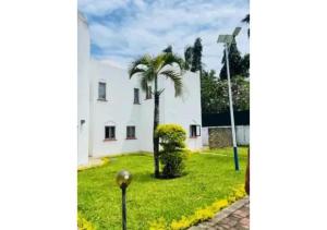 a palm tree in front of a white building at Mango Villa Mtwapa in Mtwapa