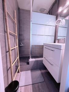 a bathroom with a shower and a sink and a stool at Appartement tout confort très proche mer in Villers-sur-Mer