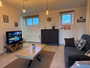 a living room with a couch and a tv at Grand T3 2 chambres avec vue sur la campagne à Bâlines in Balines