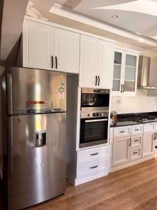 a kitchen with white cabinets and a stainless steel refrigerator at NAIBERi LUXURY HOME in Eldoret