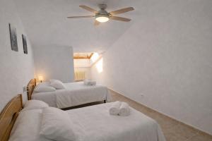 a room with three beds and a ceiling fan at Apto Espert l PISCINA l Cine l Garaje l BBQ l Wifi in Biescas