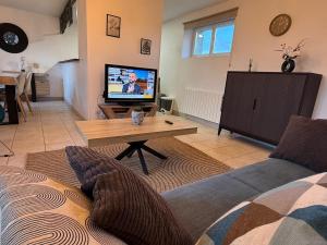 a living room with a couch and a tv at Grand T3 2 chambres avec vue sur la campagne à Bâlines in Balines