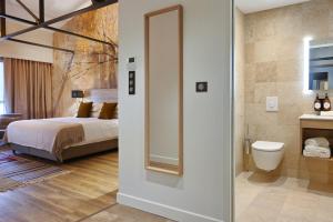 a bedroom with a bed and a bathroom with a mirror at Walnut Bistro & Suites in Eymet