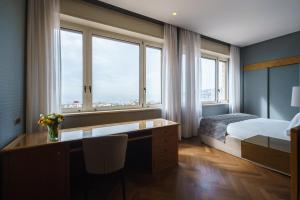 a hotel room with a bed and a desk and windows at Exe Majestic in Naples