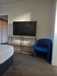a room with a tv and a blue chair at Wattleview in Lithgow