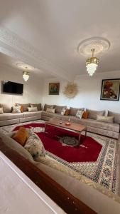 a living room with a large couch and a red rug at Résidence chez Said in Sidi Ifni