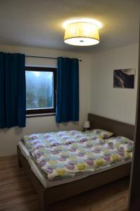 ein Schlafzimmer mit einem Bett mit blauen Vorhängen und einem Fenster in der Unterkunft Apartman #11 - Apartmanovy dom Ďumbier - Chopok Juh in Tale