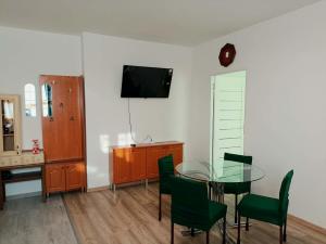 a dining room with a glass table and green chairs at Tiszti Szálló Apartman in Verpelét