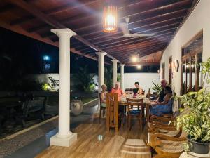 a group of people sitting at a table on a patio at Rupa Villa in Beruwala