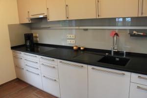 a kitchen with white cabinets and a black counter top at Ferienhaus Schünhoff in Schneverdingen