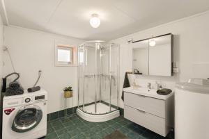 a bathroom with a shower and a washing machine at Aurora Bliss - Waterfront Jacuzzi & Sauna near Bergen in Askøy +42 photos