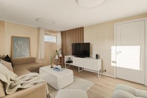 a living room with a couch and a tv at Aurora Bliss - Waterfront Jacuzzi & Sauna near Bergen in Askøy
