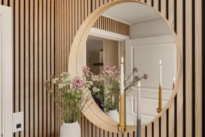 a hallway with a round mirror and flowers in vases at Aurora Bliss - Waterfront Jacuzzi & Sauna near Bergen in Askøy