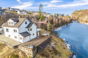 a white house on a dock next to a river at Aurora Bliss - Waterfront Jacuzzi & Sauna near Bergen in Askøy