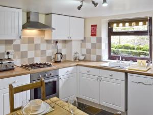 a kitchen with white cabinets and a sink at Jeremiah Cottage in Bradwell