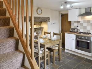 a kitchen with a table with chairs and a staircase at Jeremiah Cottage in Bradwell
