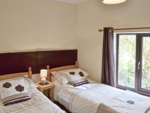 two beds in a bedroom with a window at Jeremiah Cottage in Bradwell +4 photos