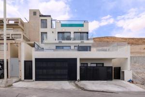 a large white house with black garage doors at וילה לה מר - וילה עם בריכה ו-3 סוויטות מדהימות עם נוף לים המלח in Neve Zohar