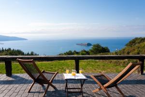 una mesa y sillas en un patio con vistas al océano en Hotel Spa Gametxo en Ibarrangelu
