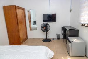 a bedroom with a bed and a fan and a television at The 4 Kays Apartment - One Bedroom in Agege