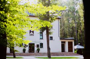 ein weißes Gebäude mit Bäumen davor in der Unterkunft Montis Hotel & Spa in Poniatowa