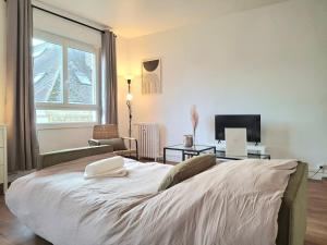 a bedroom with a large white bed and a television at Le Sweet Escape - Vue Sur La Cathédrale in Beauvais